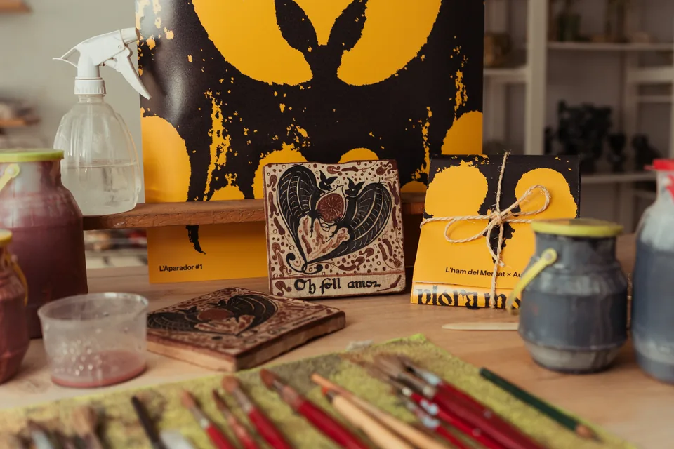 La peça, el cartell de l'Aparador #1 i el paquet lligat amb cordell, damunt del banc del taller.