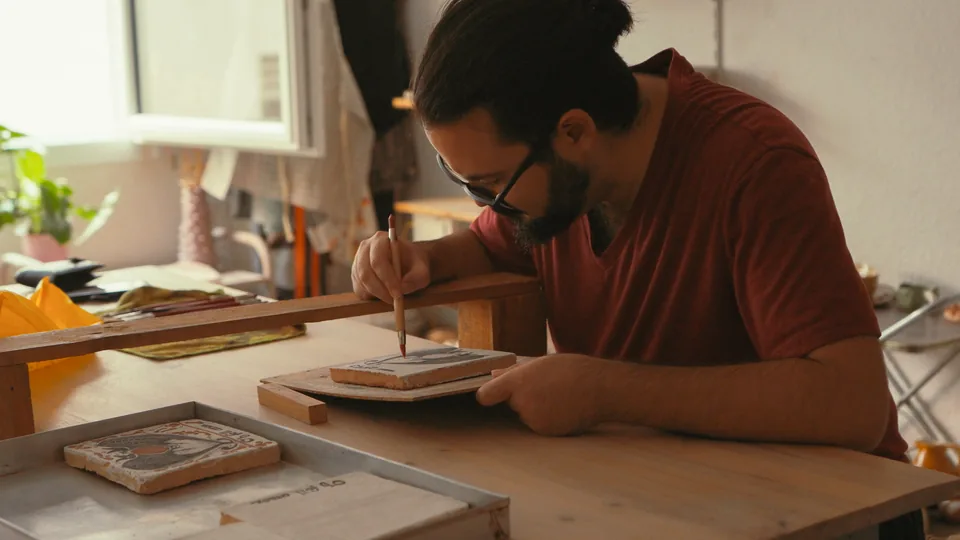 Fernando pintant un socarrat amb el pinzell, al taller.